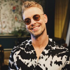 man in black and white floral button up shirt wearing brown sunglasses